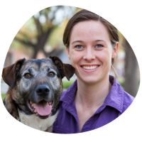 A photo of Keely, brown haired lady holding a dog and smiling